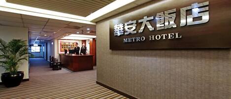 A hotel reception area with a sign reading "METRO HOTEL" in both English and another language.