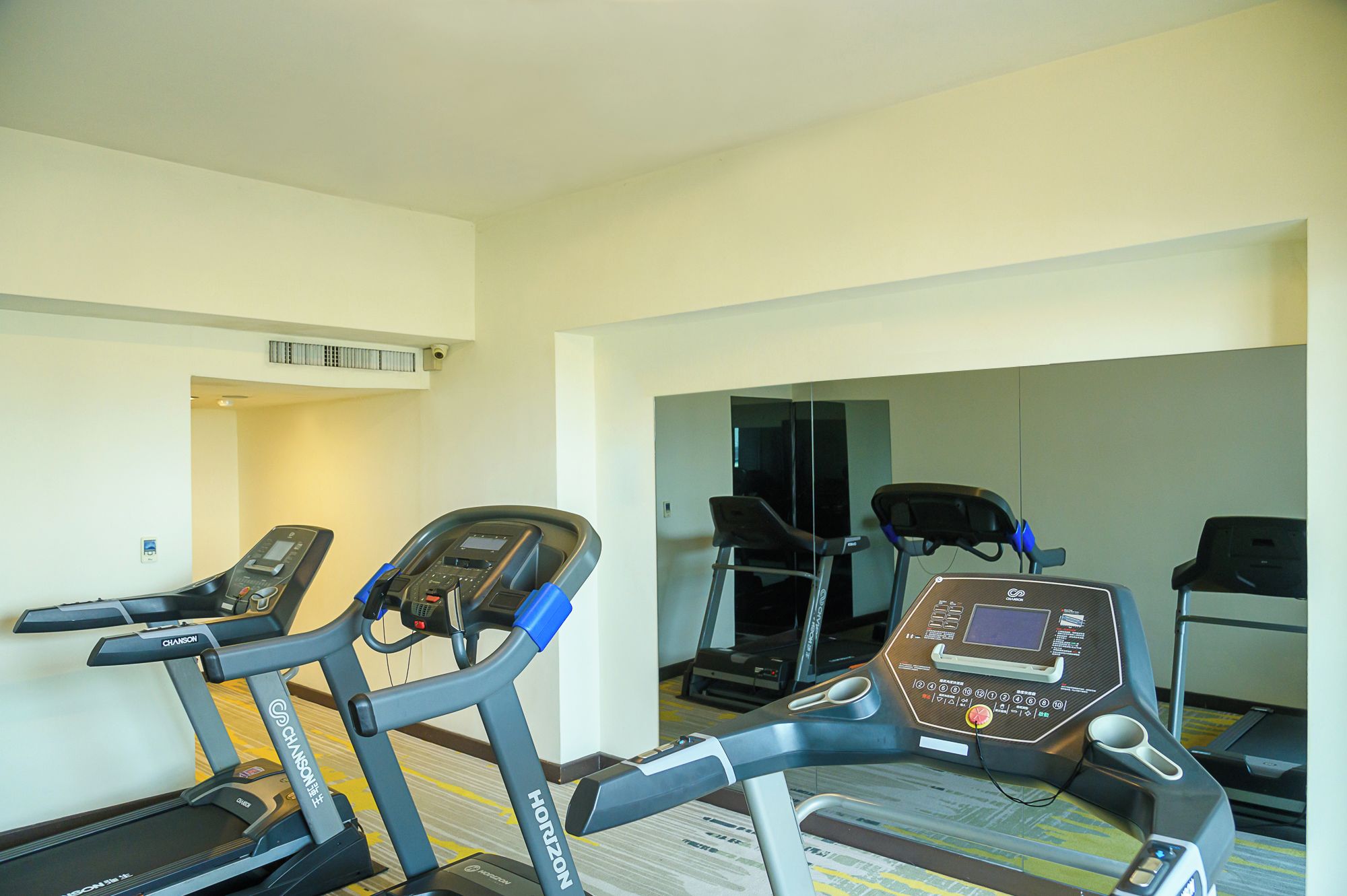 A hotel fitness room with treadmills and a mirrored wall.
