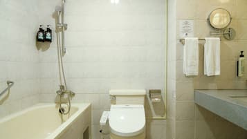 Un baño con bañera, inodoro y ducha. Hay dos botellas de champú en la pared.