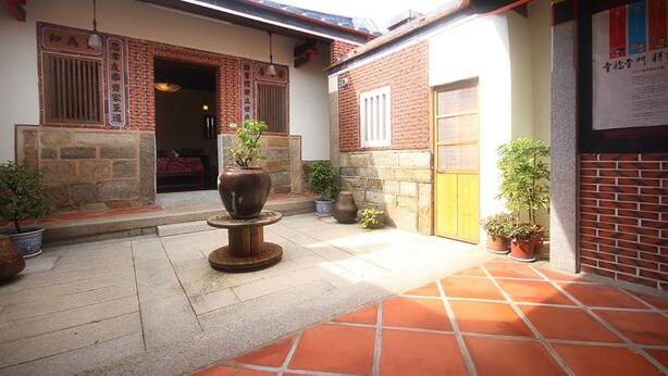 Une cour avec un sol en pierre, des plantes en pot et une entrée de style japonais traditionnel.