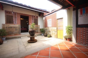 Un patio con suelo de piedra, plantas en macetas y una entrada de estilo tradicional japonés.