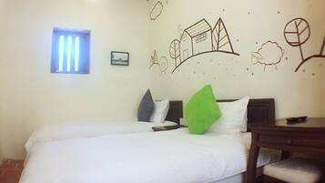 A bedroom with two beds, a small window, and a wall decorated with simple line drawings.