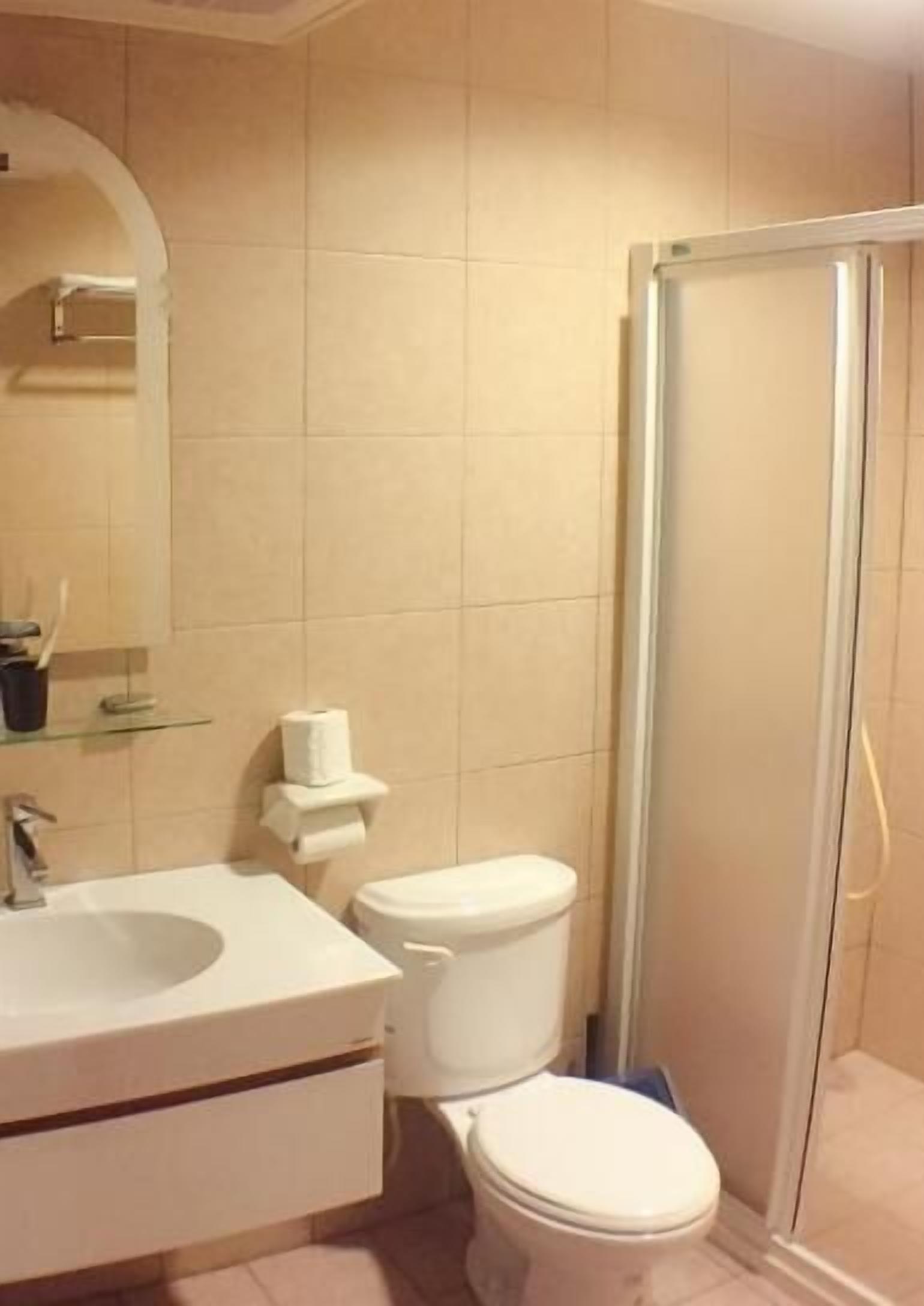 Un baño con lavamanos, inodoro y cabina de ducha de vidrio.