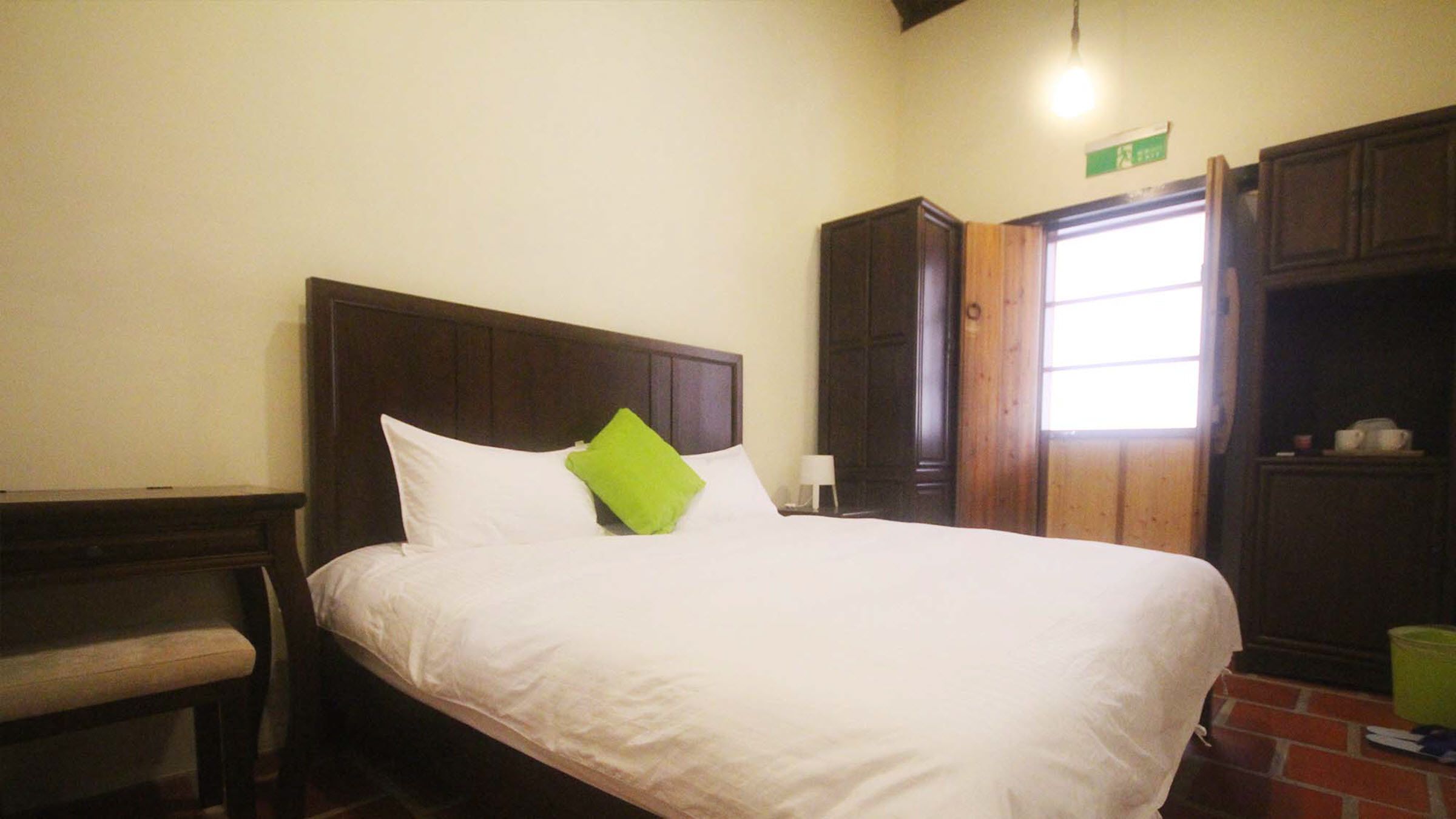 A hotel room with a bed, a desk, and a wardrobe.