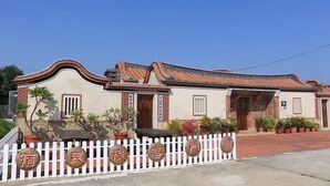 Un bâtiment traditionnel avec un toit incurvé, une clôture blanche en piquets et des plantes en pot.