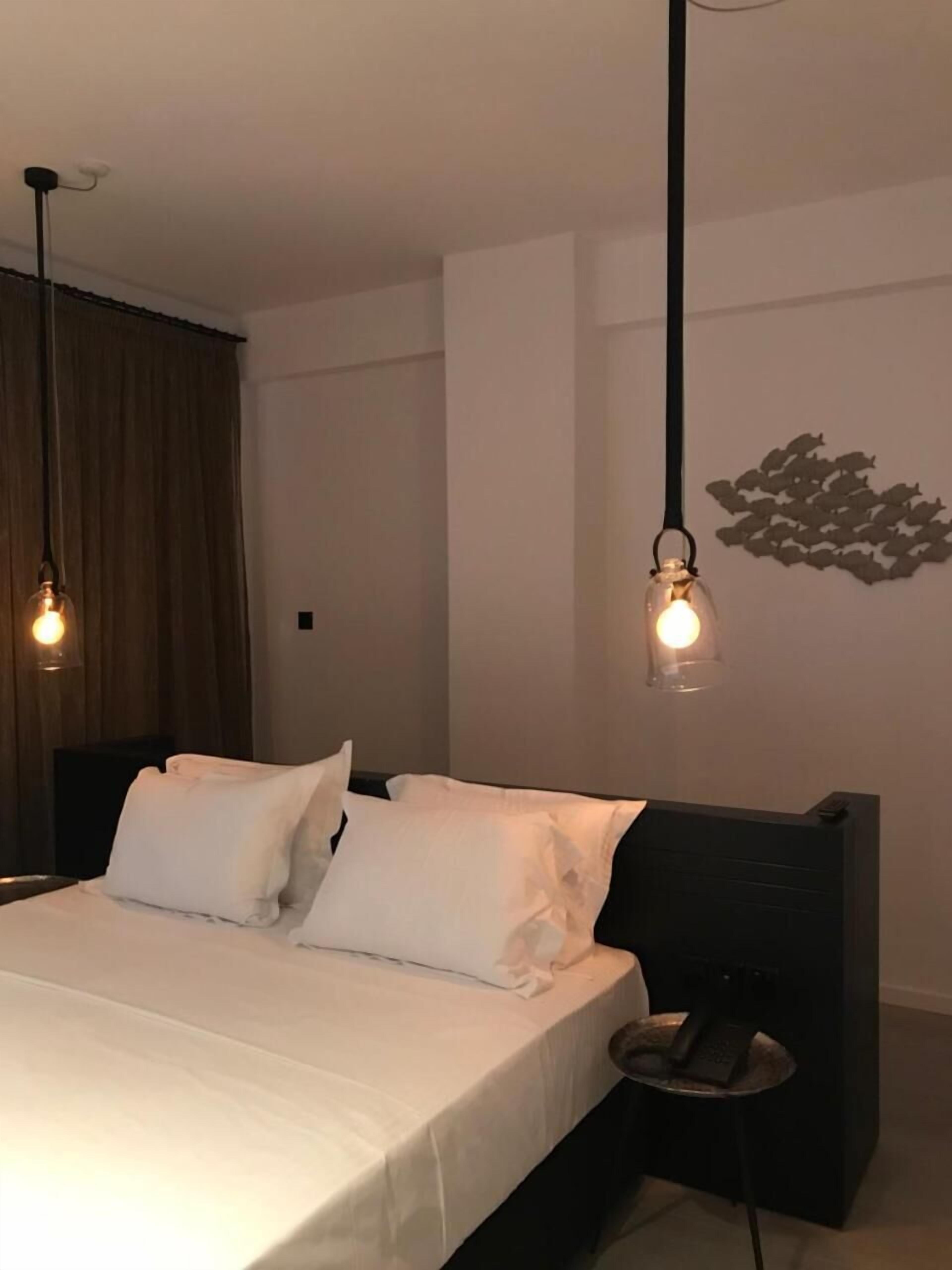 A bedroom with a bed, bedside table, and a wall-mounted light fixture.