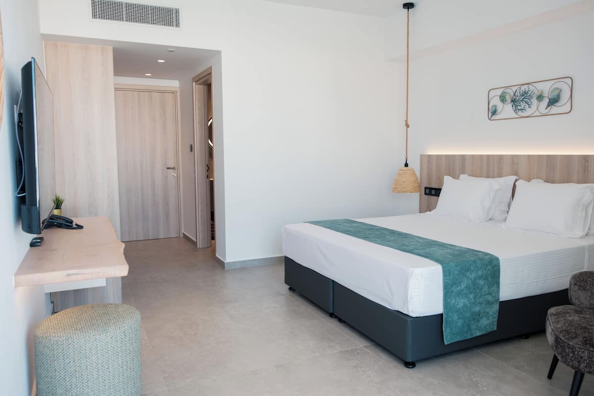 Una habitación de hotel moderna con una cama, un escritorio con una computadora, una silla y un televisor.