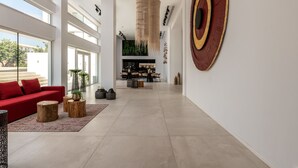 Un salón espacioso con un sofá rojo, mesas de centro de madera y una gran obra de arte en la pared.