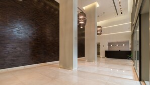 Um lobby moderno com piso lustroso, parede de tijolos escuros e balcão de recepção.
