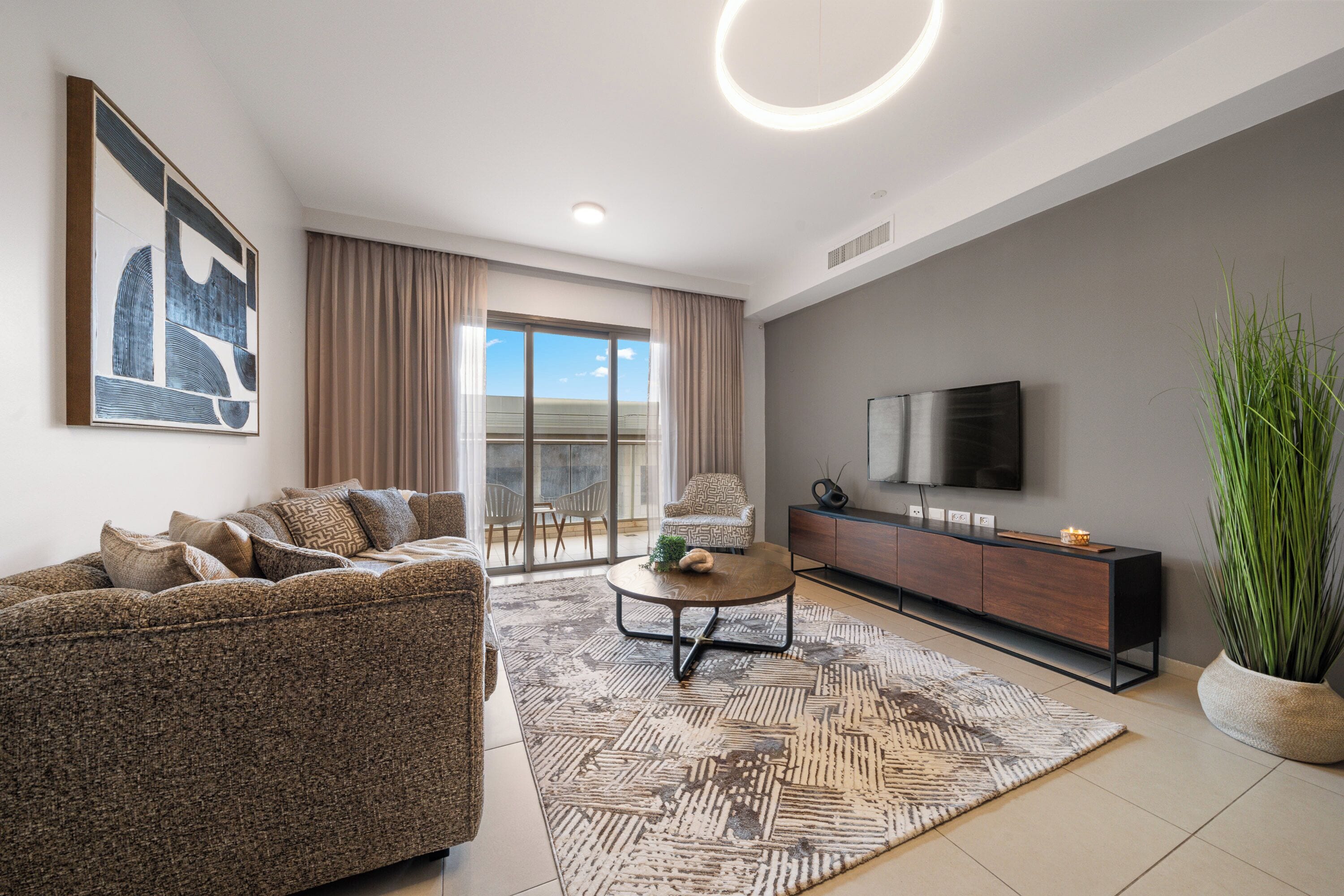 A modern living room with a sofa, coffee table, and a TV on a wall.