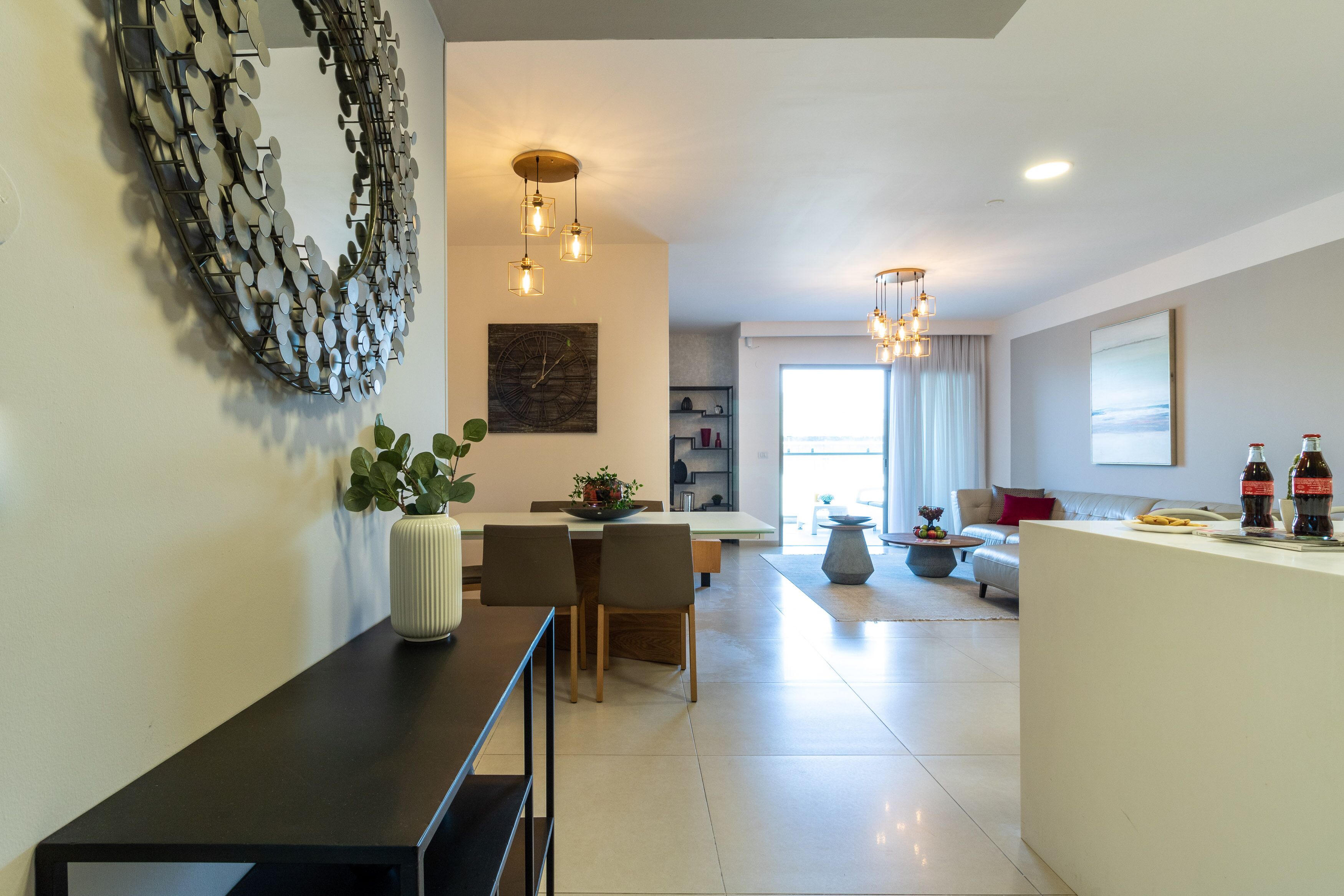 Un salon moderne avec un coin repas, agrémenté d’une grande œuvre d’art abstraite au mur, d’une plante en pot et d’une table basse.