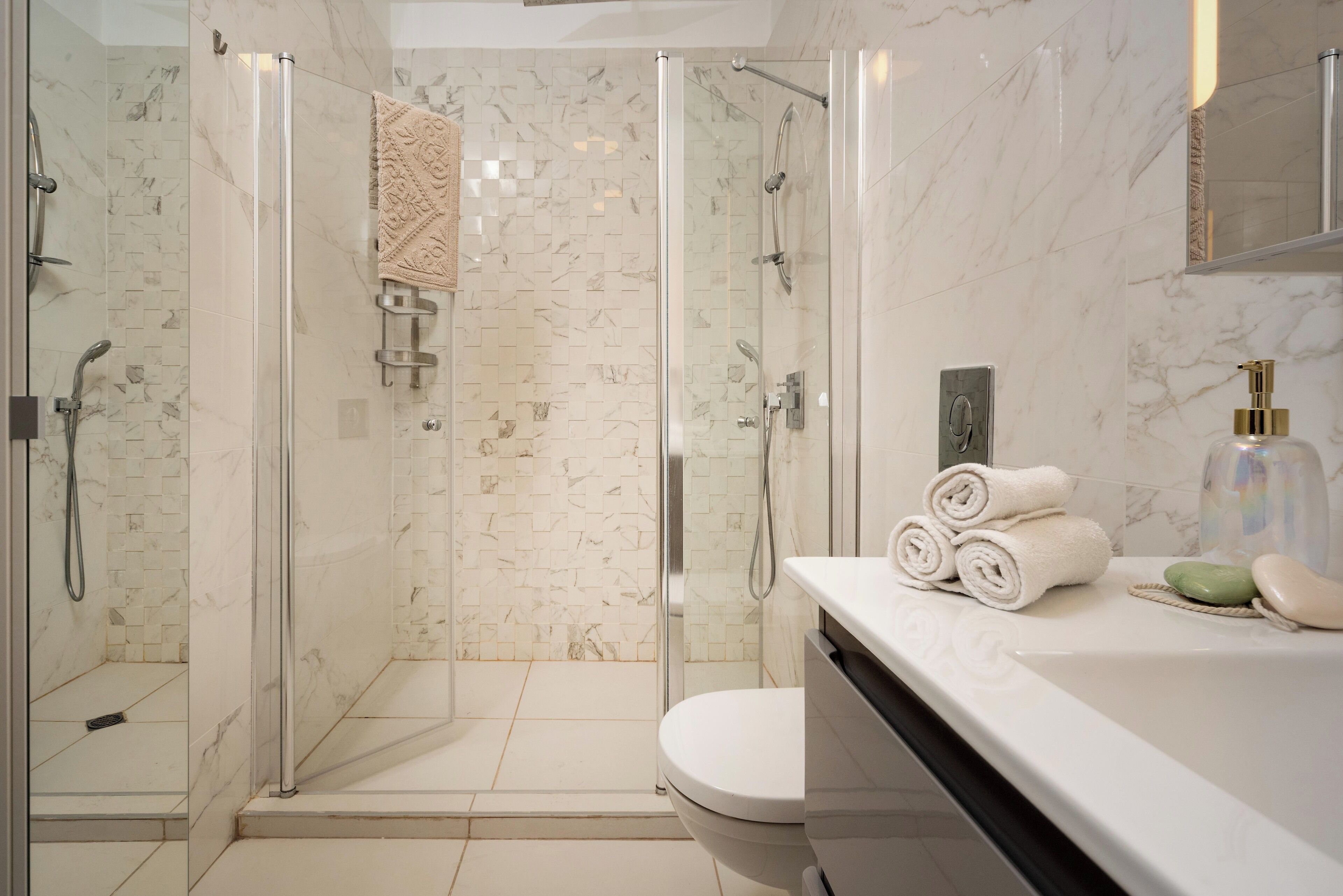 A modern bathroom with a glass-enclosed shower, a toilet, and a vanity with toiletries.