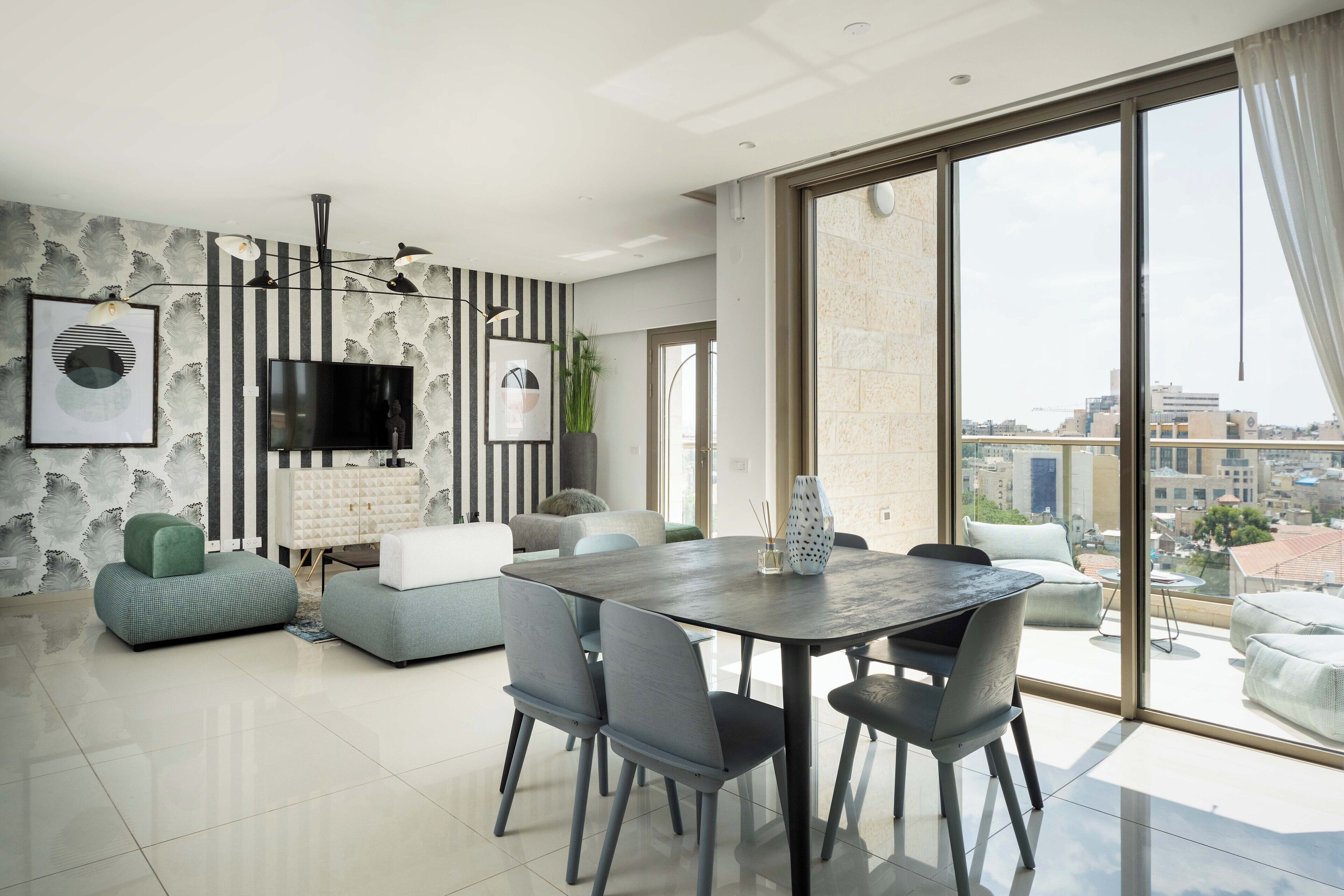 Un salon moderne avec un coin repas, de grandes fenêtres et une vue sur la ville.