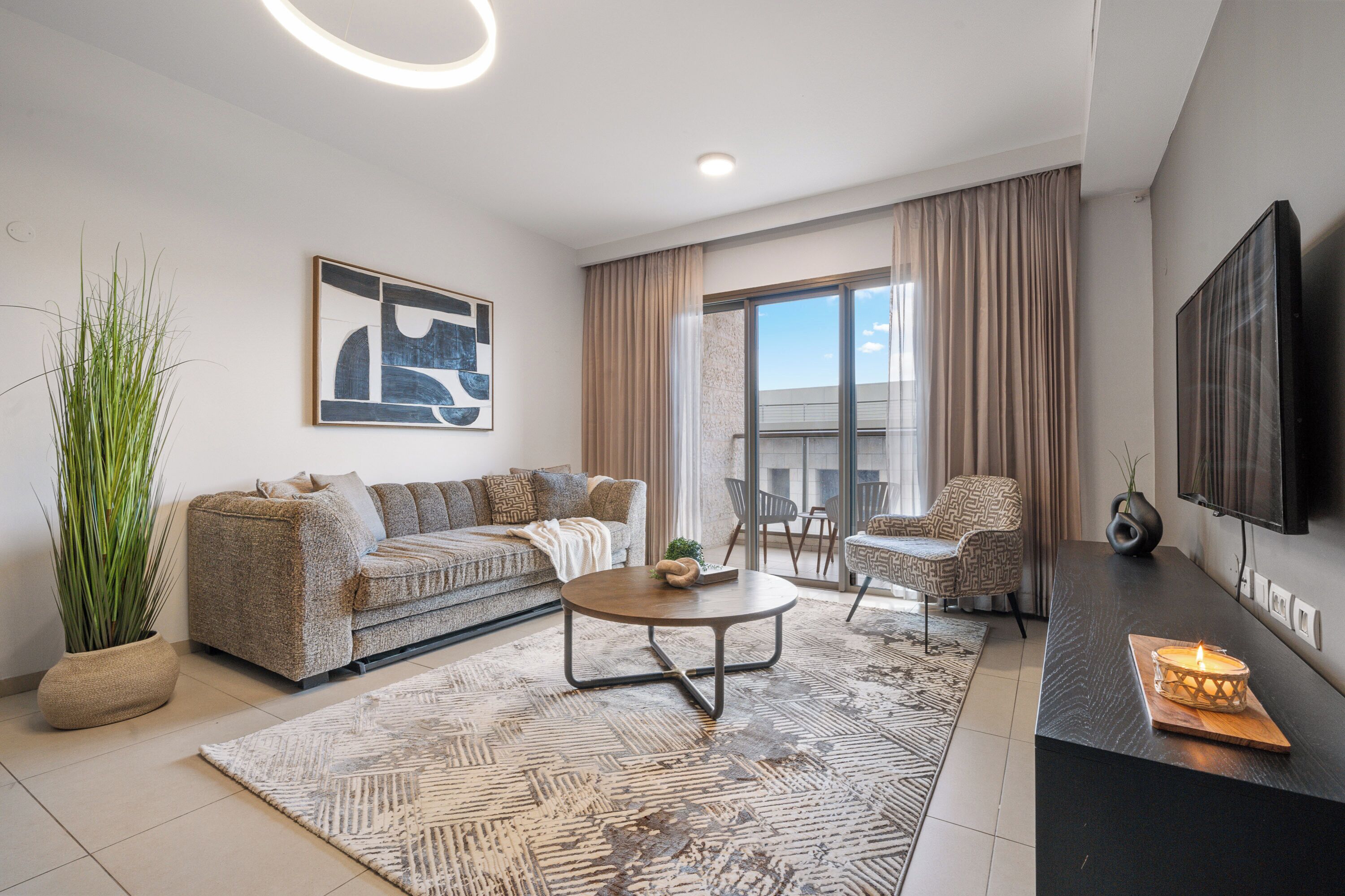 Ein modernes Wohnzimmer mit Sofa, Sessel, Couchtisch und Flachbildfernseher.
