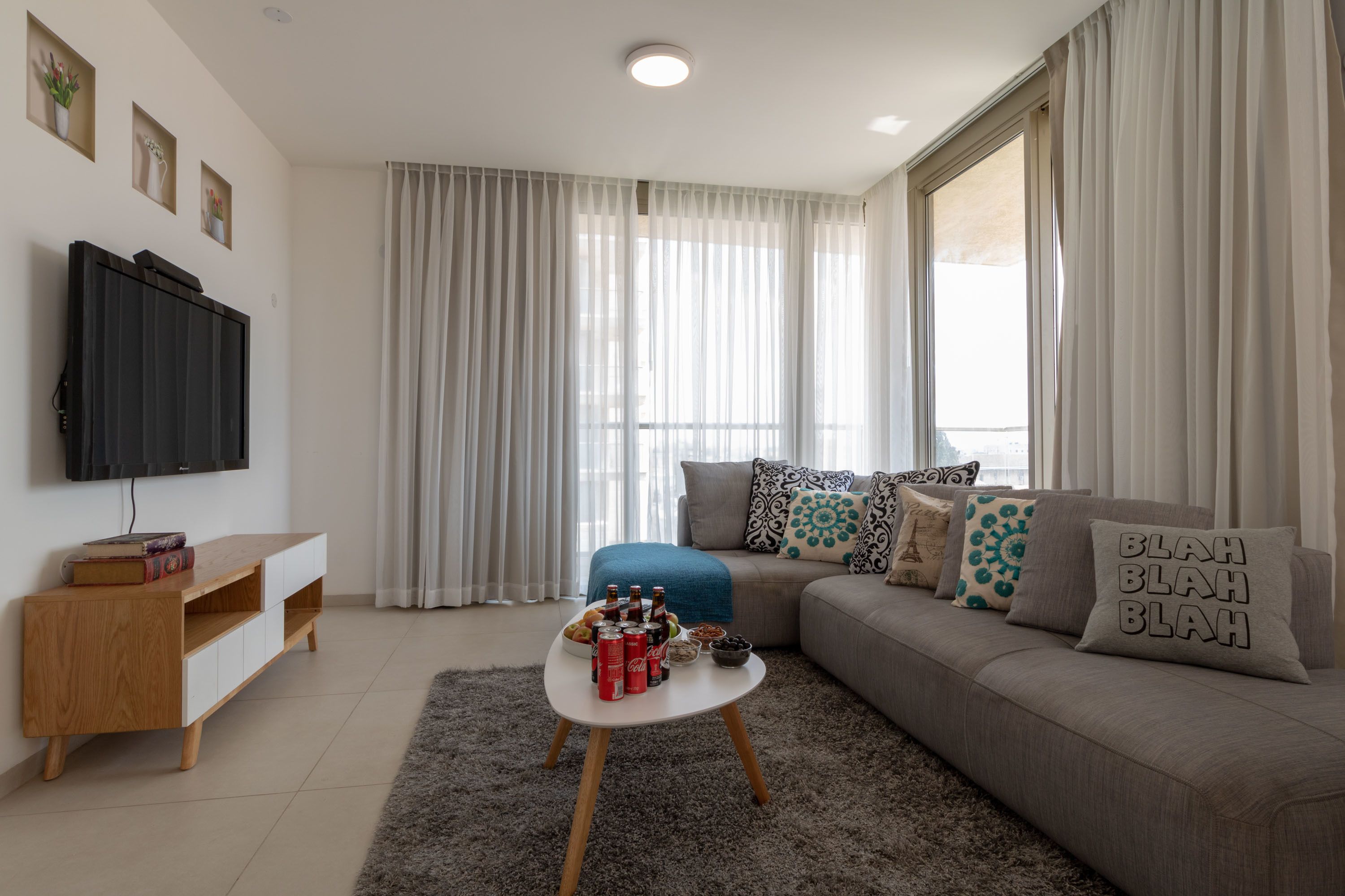 Una sala de estar moderna con un sofá, una mesa de centro y un televisor montado en la pared.