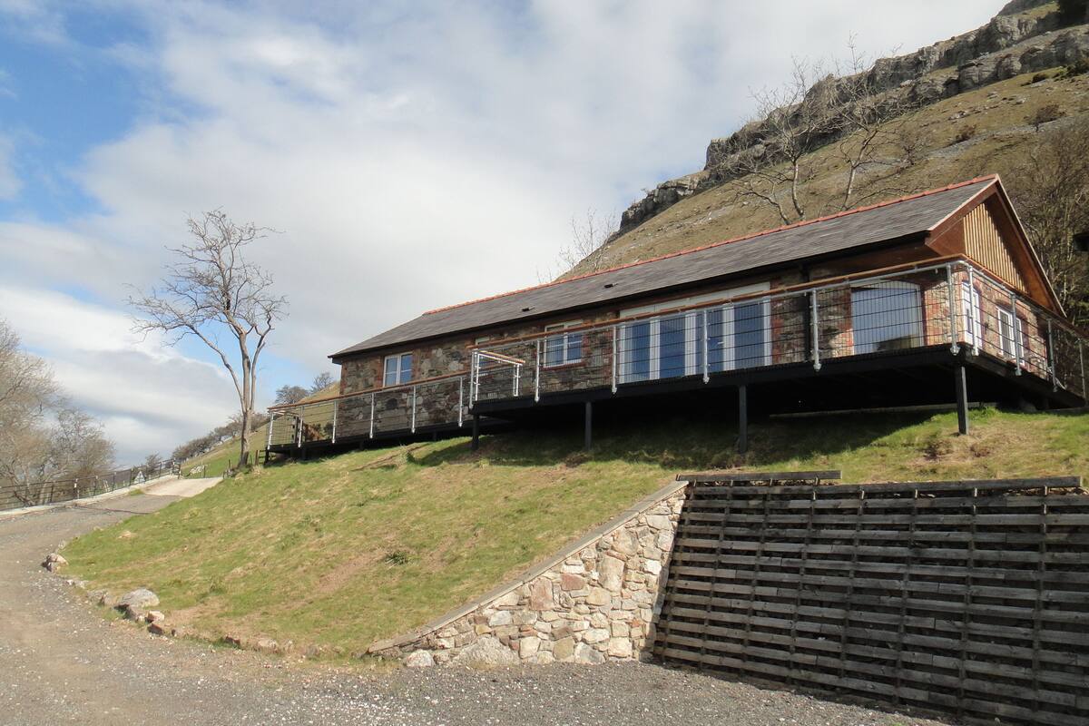 A stone house with a wooden deck and a stone wall.