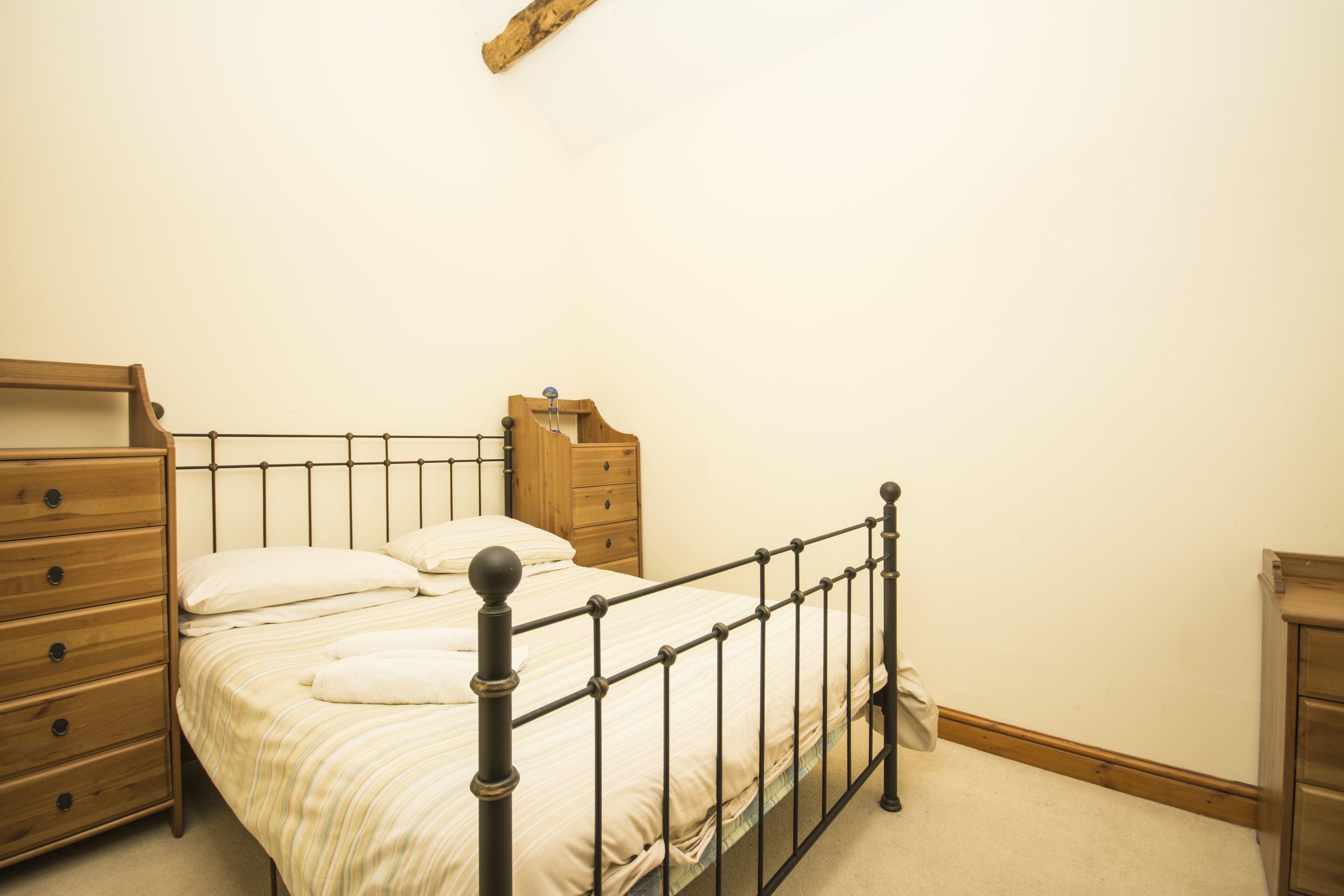 A bedroom with a metal bed frame, wooden dresser, and a nightstand.