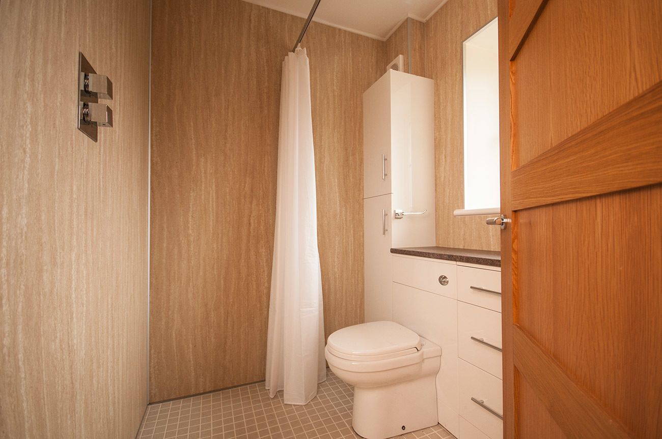 Un baño con ducha, inodoro y armarios de madera.