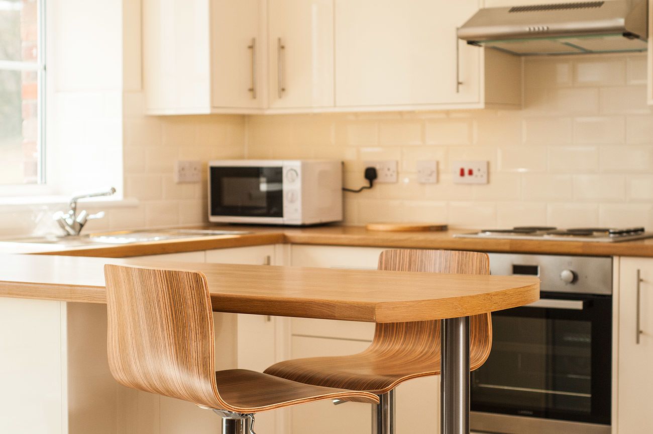 A modern kitchen with a wooden table and chairs, a microwave, and an oven.