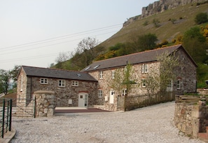 A stone building with a gravel driveway and a wooden fence. - Panorama Cottages (Llangollen)