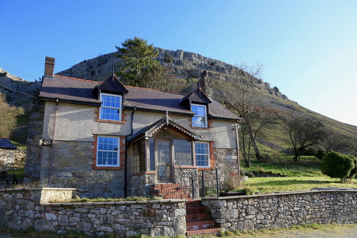 A stone house with a gabled roof, a chimney, and a small porch with steps.