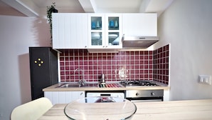 Een moderne keuken met witte kastjes, een gasfornuis en een betegelde spatwand.