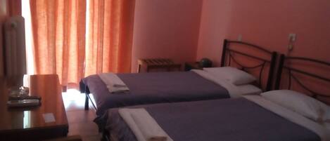 Habitación de hotel con dos camas, un escritorio y una ventana con cortinas.