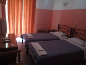 Une chambre d’hôtel avec deux lits, un bureau et une fenêtre avec des rideaux.