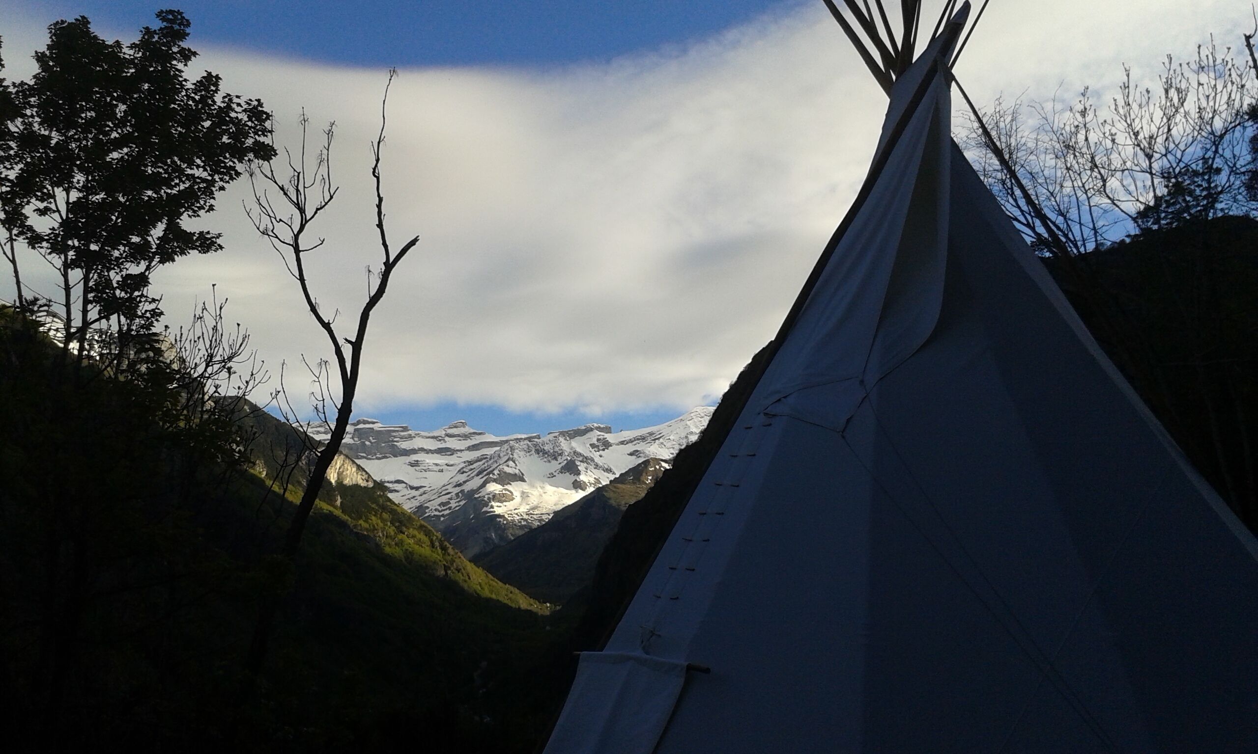 A white teepee with a mountain view in the background.