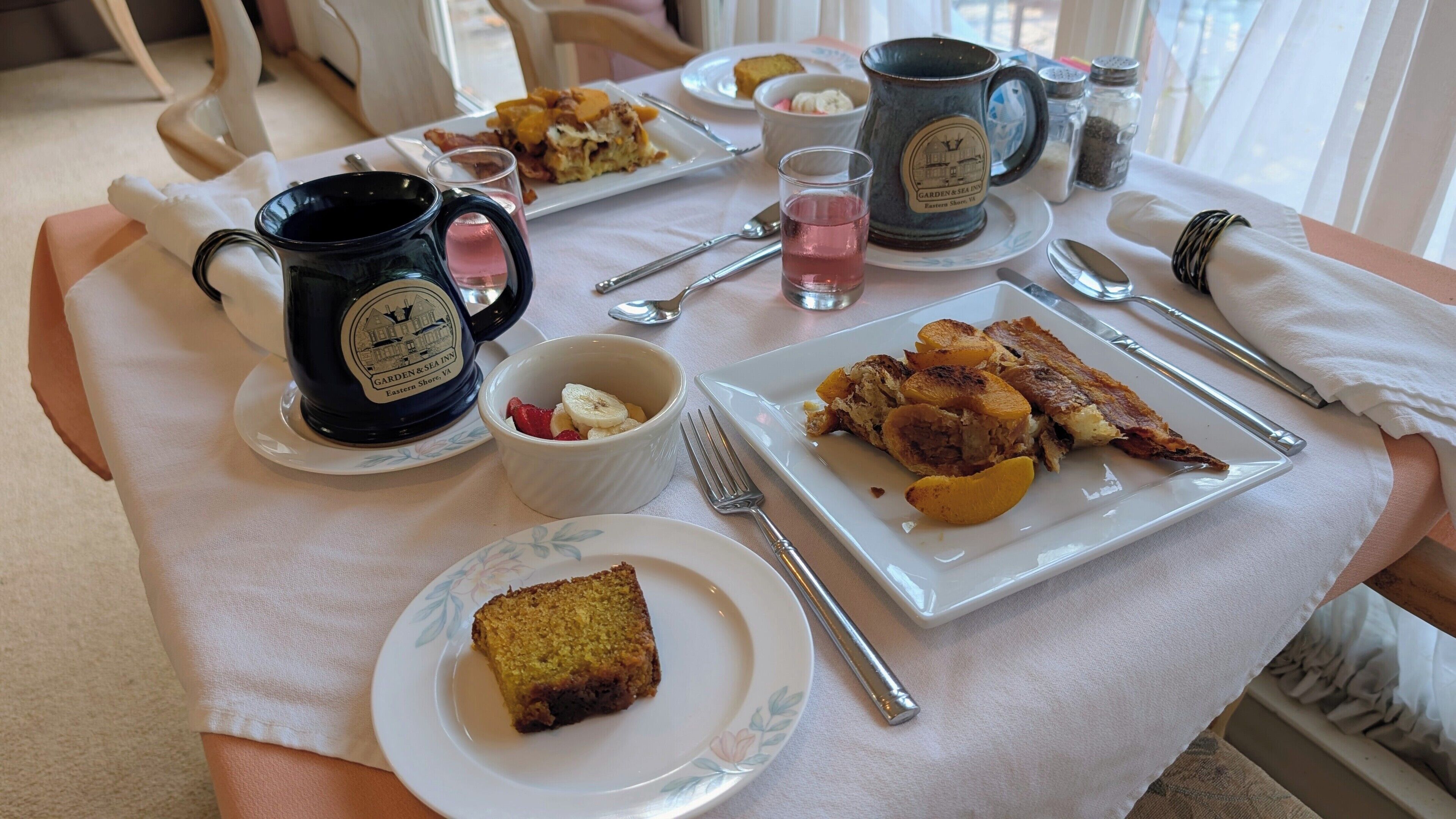 Una mesa dispuesta con cosas para el desayuno, como tostadas, una rebanada de pastel y una taza.