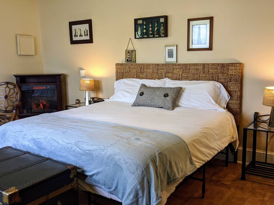 Una camera da letto ordinata con un letto grande, un camino e una valigia sul pavimento.