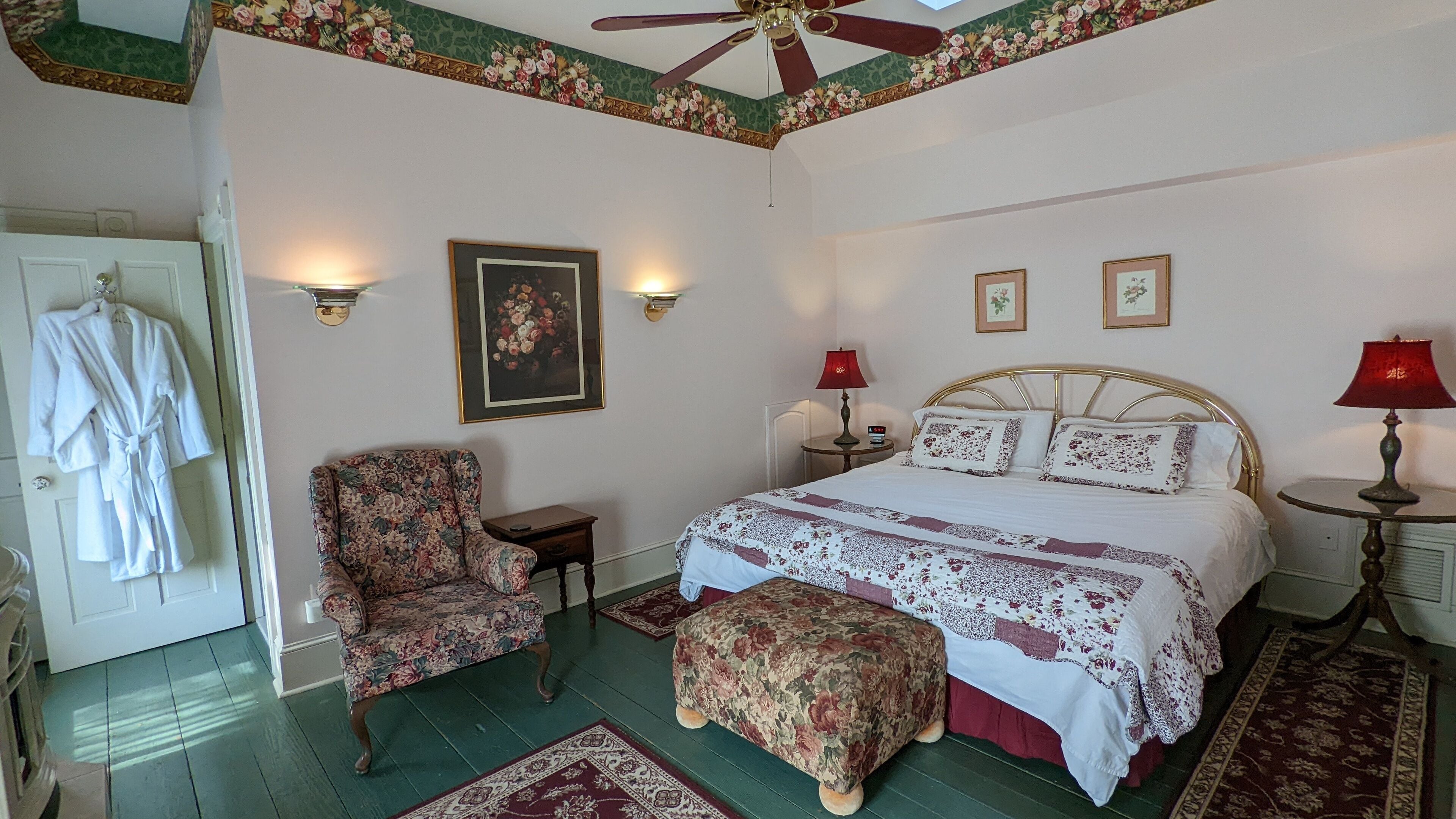 A bedroom with a large bed, a chair, a small table, and a wardrobe.