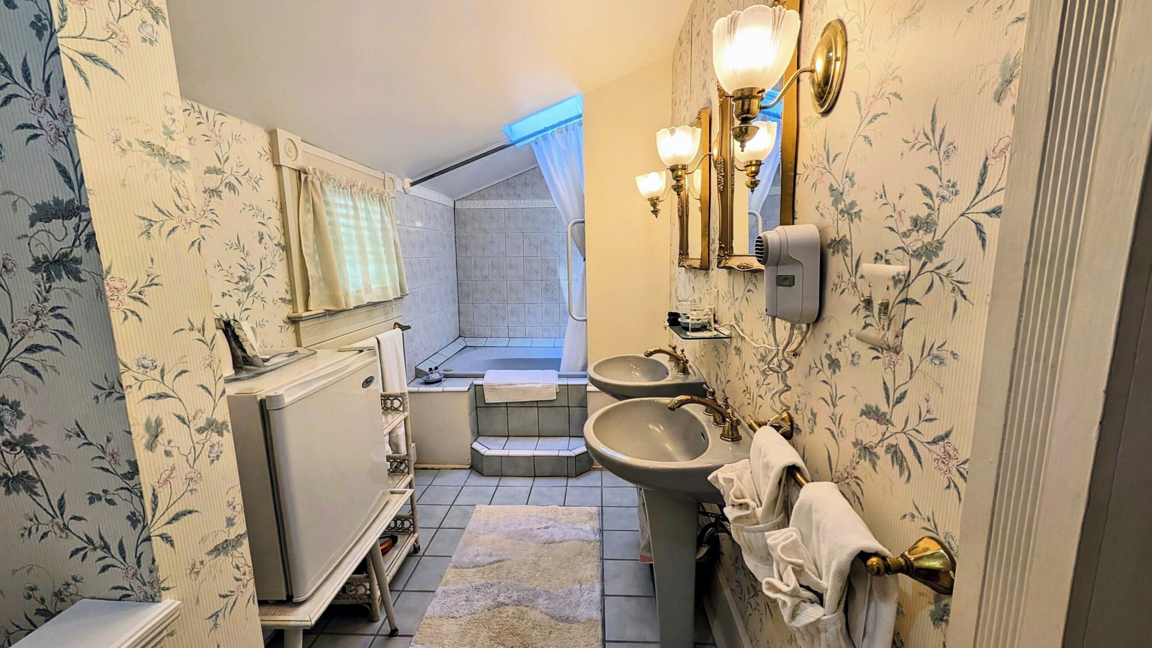 A bathroom with a shower, two sinks, a radiator, and a towel rack.