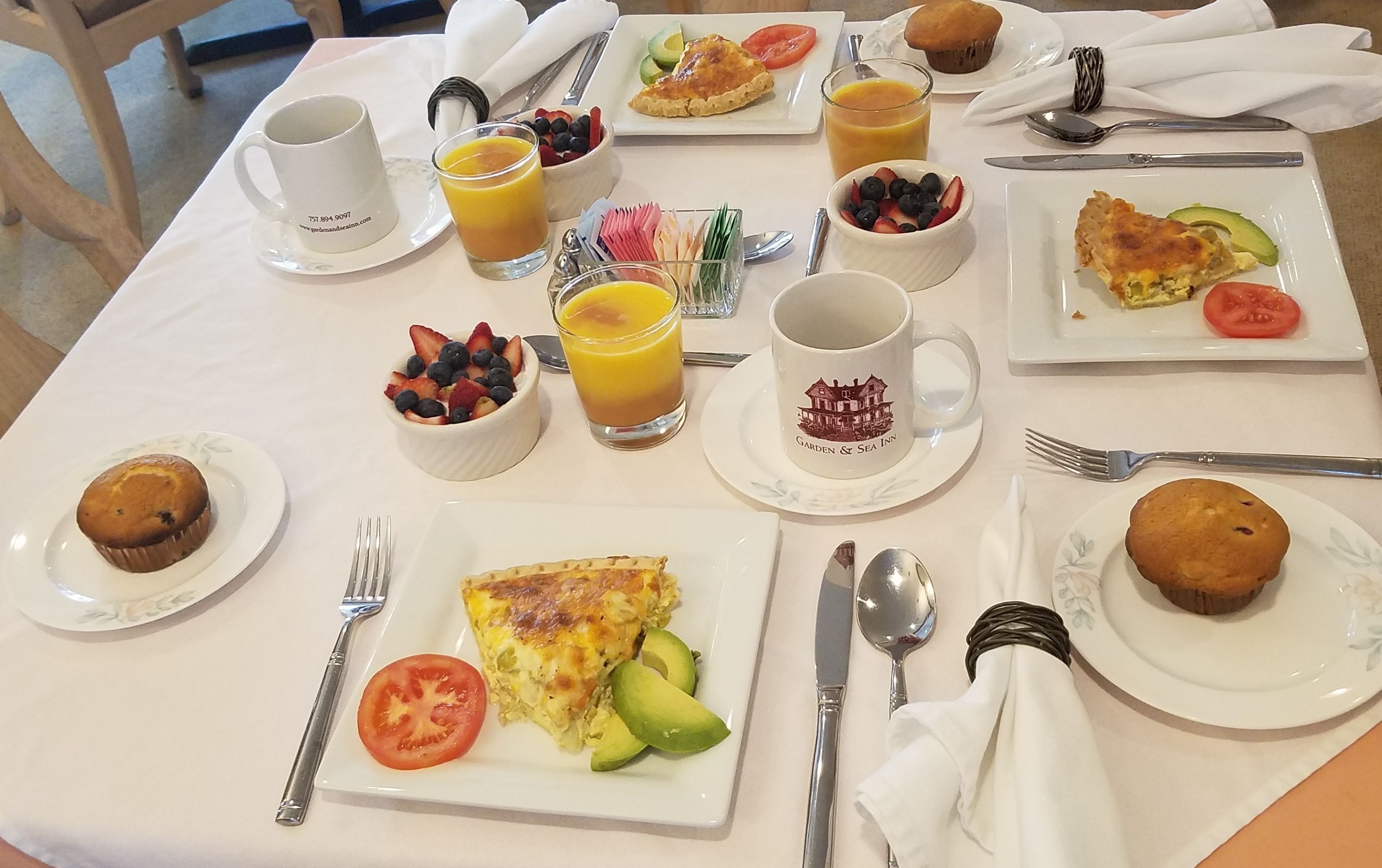 Ein Frühstückstisch mit verschiedenen Speisen, darunter Muffins, einer Obstschale und einem Glas Orangensaft.