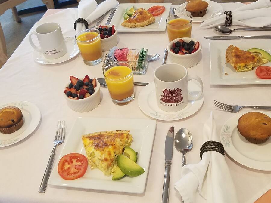 Una tavola per la colazione con diversi piatti, tra cui muffin, una ciotola di frutta e un bicchiere di succo d'arancia.