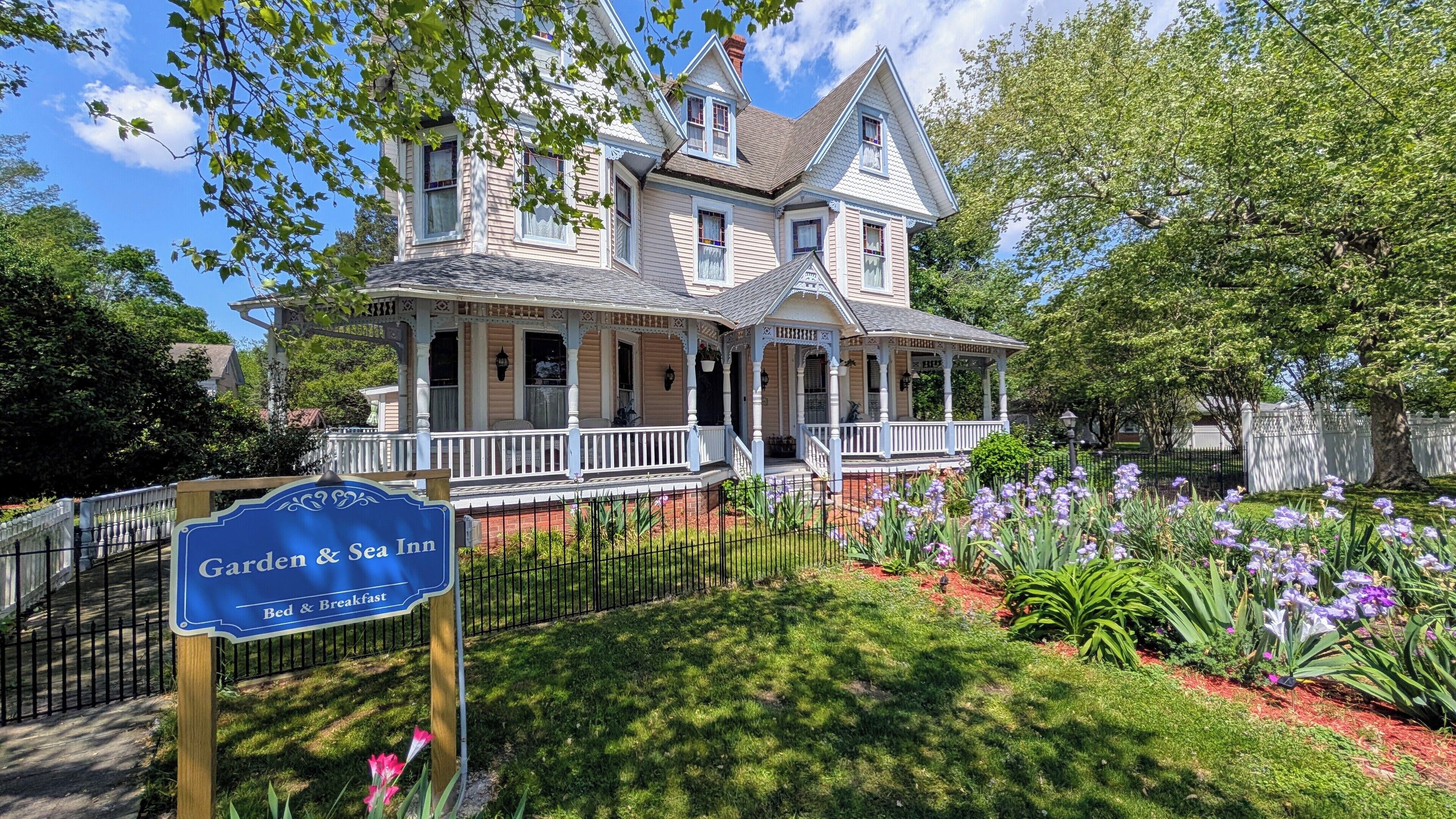 A large, two-story house with a porch and a sign indicating it is a Garden & Sea Inn offering Bed & Breakfast.