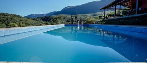 Una piscina al aire libre, sombrillas, sillones reclinables de piscina