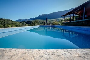 Uma piscina com água azul cristalina, rodeada por um deck de pedra.