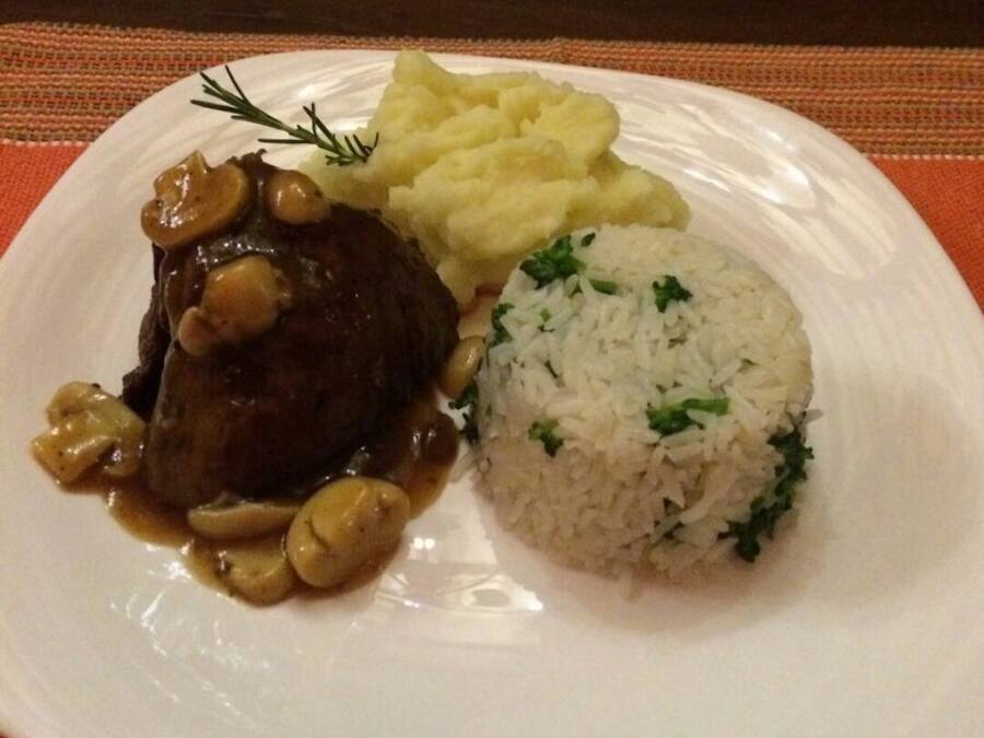 A plate with a beef steak, mashed potatoes, and rice.