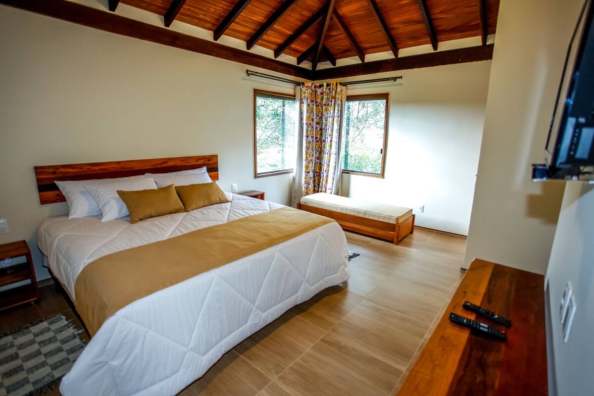 A bedroom with a large bed, a smaller bed, a desk, and a TV.