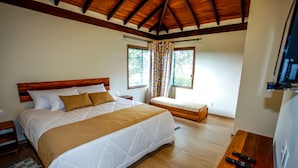 A bedroom with a large bed, a smaller bed, a desk, and a TV.