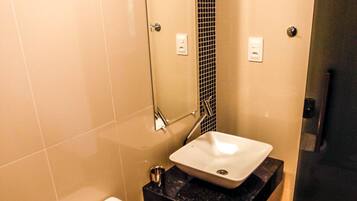 Un baño moderno con inodoro blanco, lavamanos negro y zona de ducha.