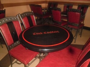 A round table with 'Club Comfort' branding, surrounded by red upholstered chairs with metal armrests. - Comfort Hotel (Thika)