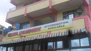 Un edificio de varios pisos con un letrero que indica “ALOJAMIENTO DISPONIBLE” al nivel de la calle.