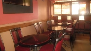 Un restaurante con mesas redondas y sillas tapizadas en rojo.