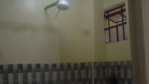 Una habitación con ventilador de techo blanco, ventana con marco rojo y pared de azulejos con un borde decorativo.