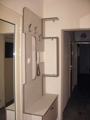 Quarto de hotel com escrivaninha embutida, telefone e espelho.