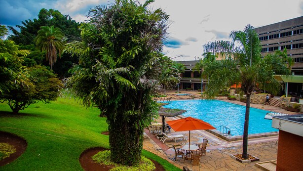A hotel pool area with a swimming pool, lounge chairs, and a palm tree. - Utalii Hotel (Nairobi)
