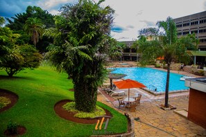 A hotel pool area with a swimming pool, lounge chairs, and a palm tree. - Utalii Hotel (Nairobi)