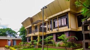 A modern building with a flat roof, multiple balconies, and a well-maintained garden with various plants. - Utalii Hotel (Nairobi)